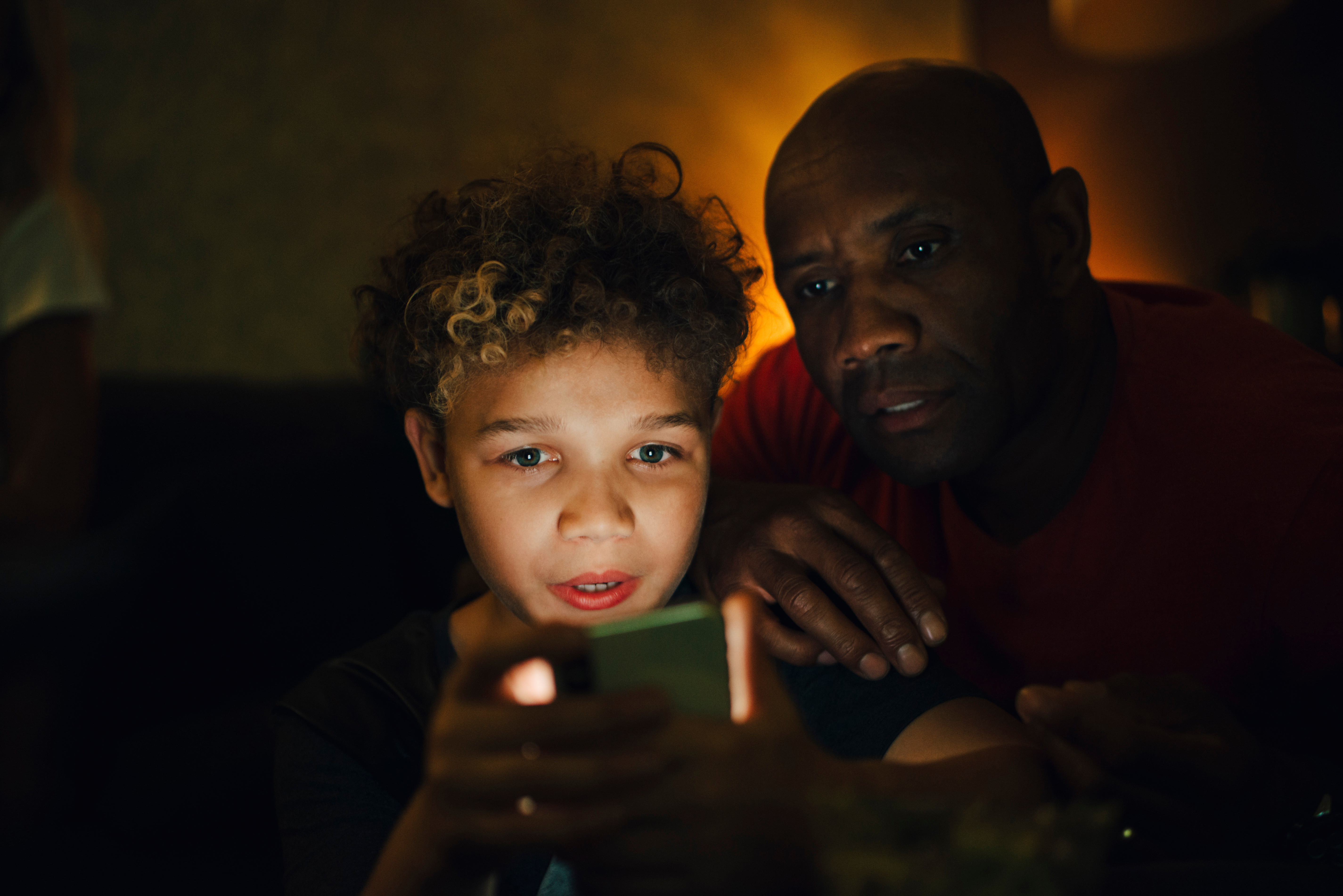 Pojke och man tittar på surfplatta mörkt rum