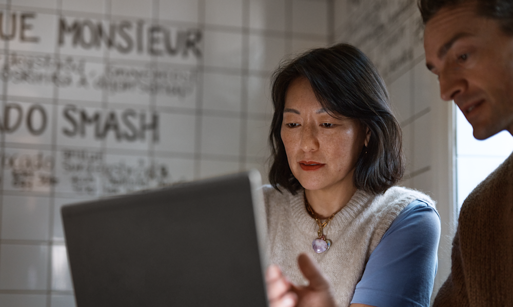 Man visar kvinna på laptop på café