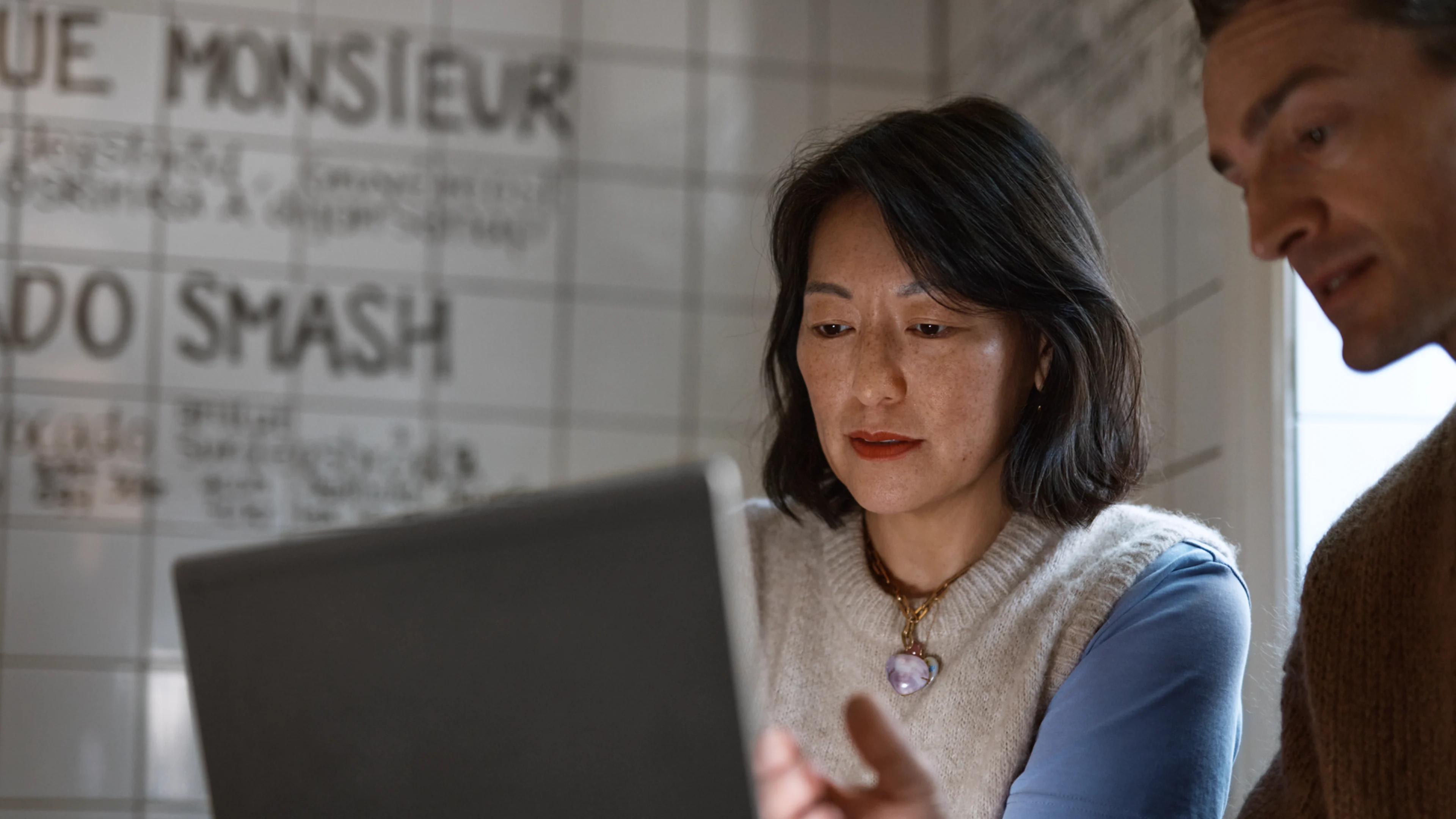 Man visar kvinna på laptop på café