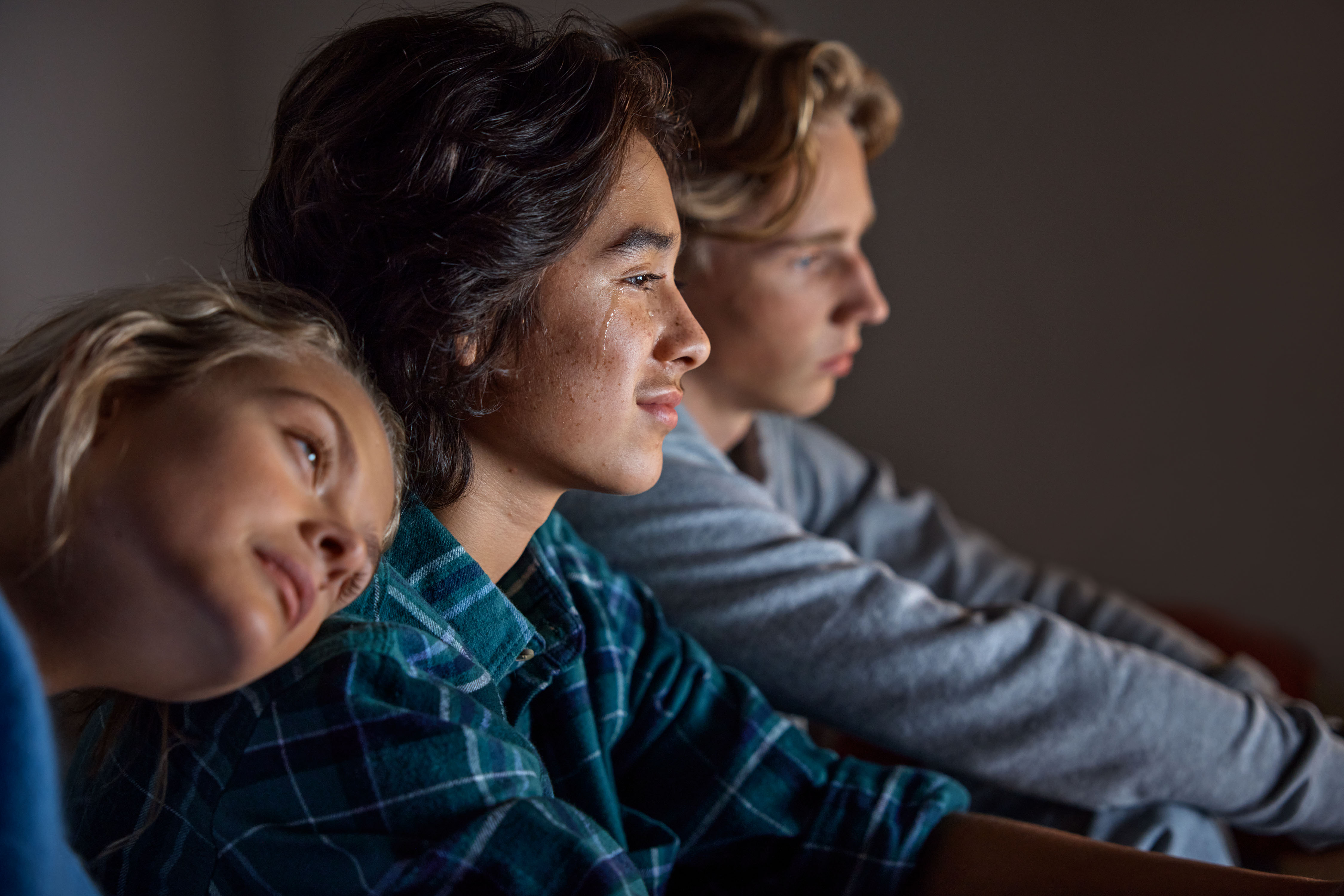 Ungdomar ser på tv tillsammans mysig stämning men något verkar sorgligt eller lyckligt