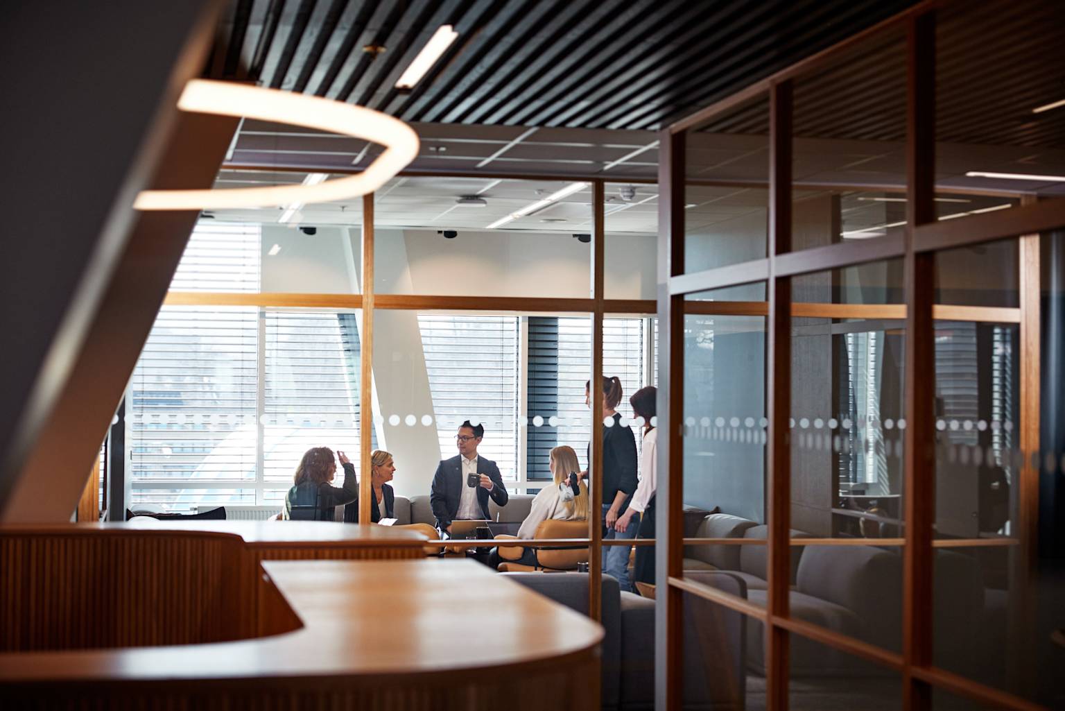 Personer som samtalar i ett konferensrum med väggar av glas.