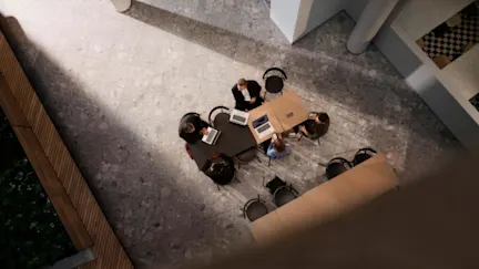 Konferensbord med arbetande människor och datorer sett ovanifrån.