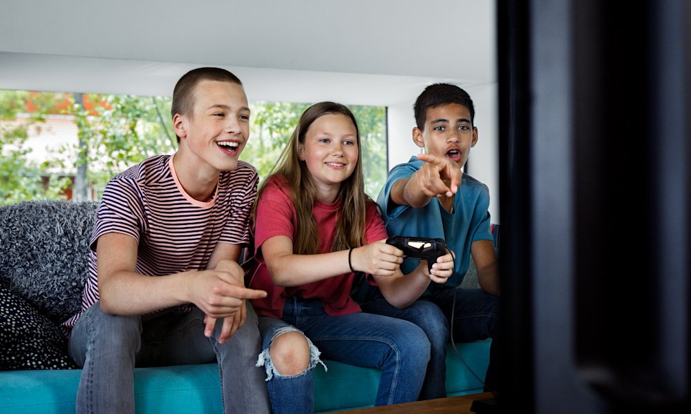 Tre ungdomar spelar tv-spel.