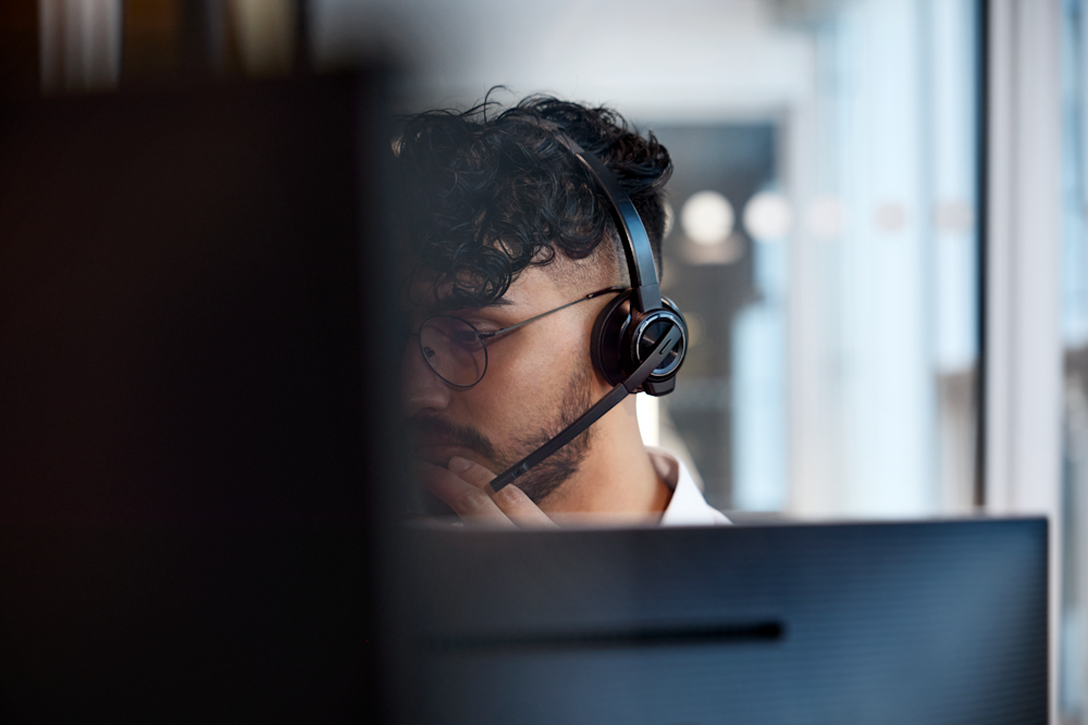 En man med hörlurar som tittar på en dator.