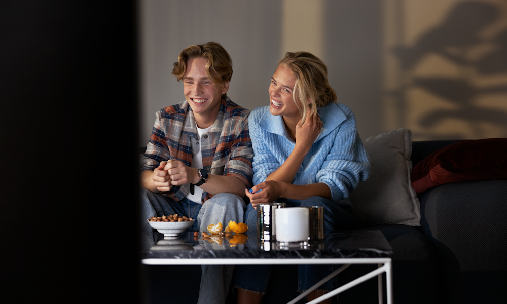 Ungt par tittar på tv och streaming från Telia Play.
