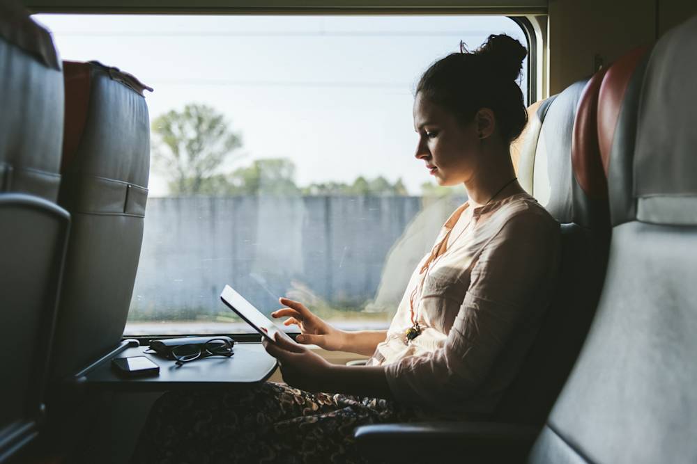 Kvinna på ett tåg som tittar på en surfplatta
