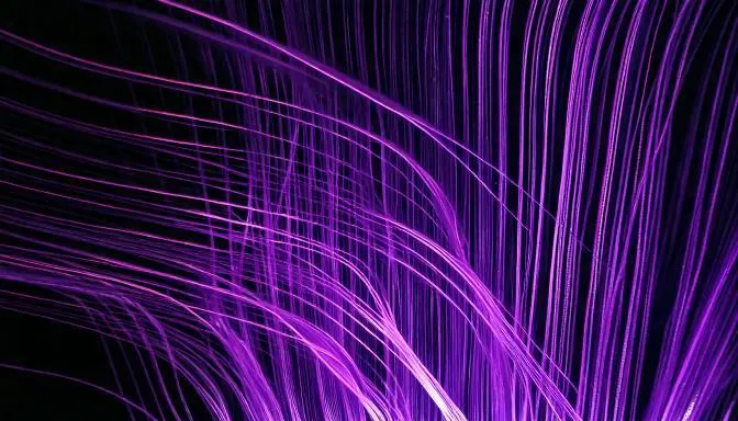Mörk bild med lila streck som ska symbolisera fibertrådar