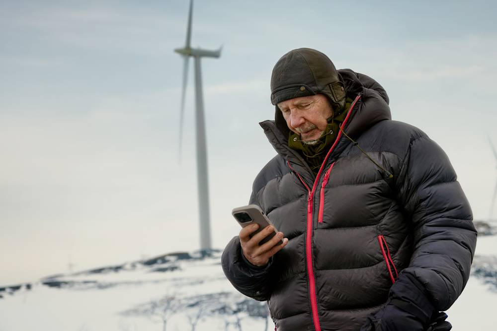 Äldre man i fjällmiljö tittar i mobiler