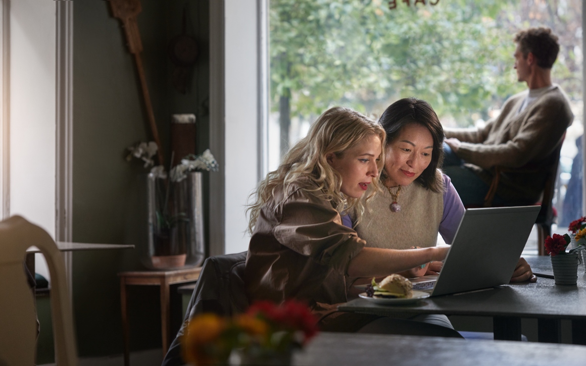 Två personer på café sitter framför laptop tillsammans. 