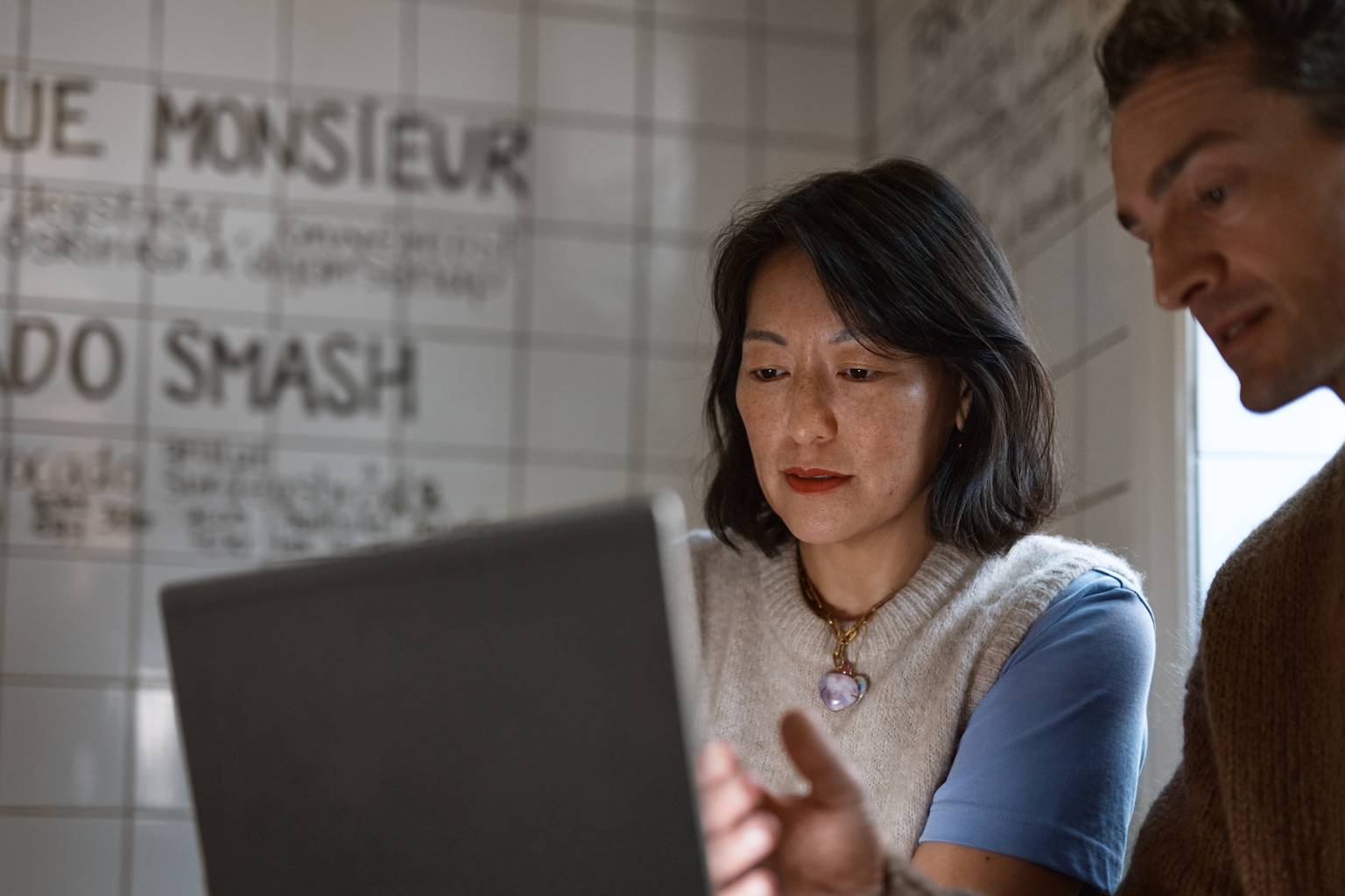 Kvinna och man oroade för DDos-attack framför laptop på café