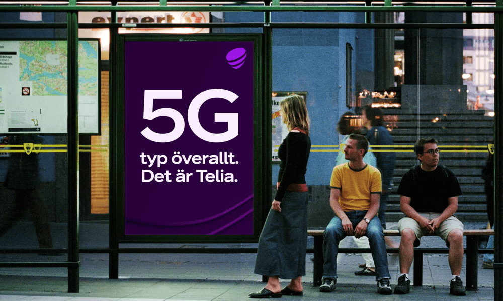 Bild som visar reklamtavla för Telia utomhus i busskur med människor