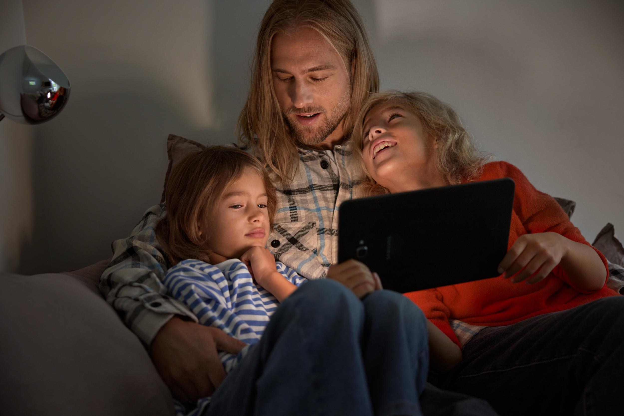 Bild på pappa med barn i soffa med surfplatta