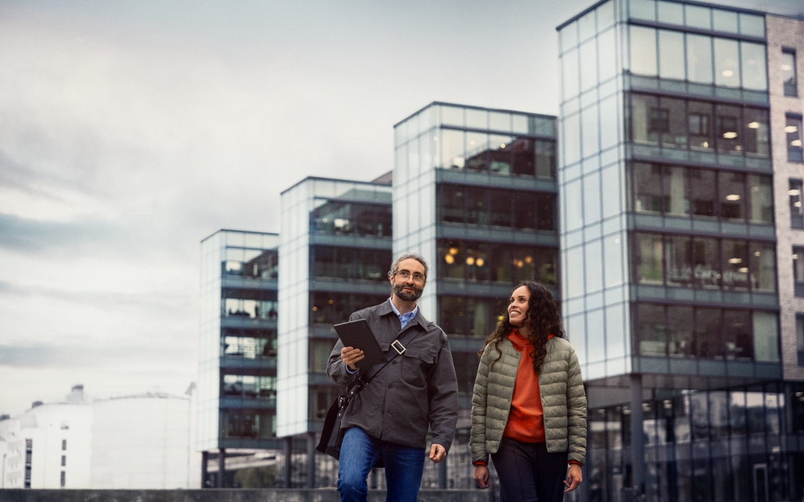 Man och kvinna promenerar från kontor höghus