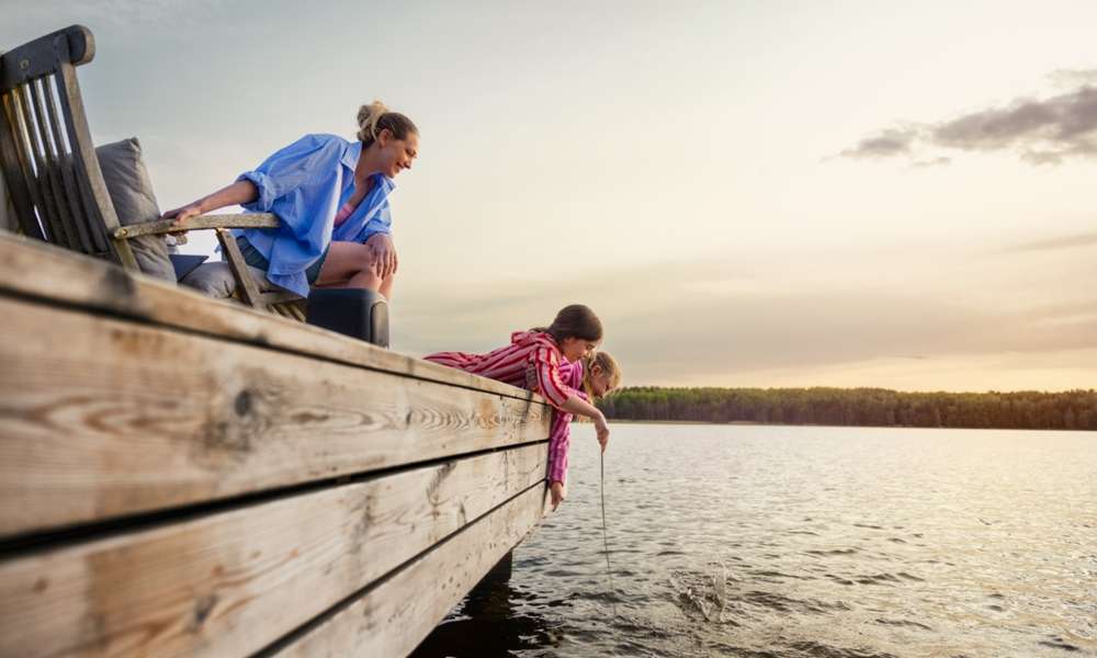 Mamma och barn fiskar från brygga