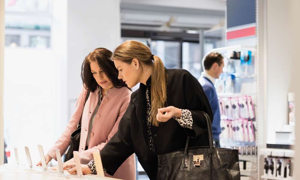 Två kvinnor tittar på nya mobiltelefoner i en butik.