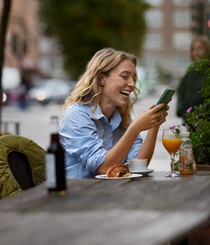 Kvinna arbetar med mobil i Telias nät på café