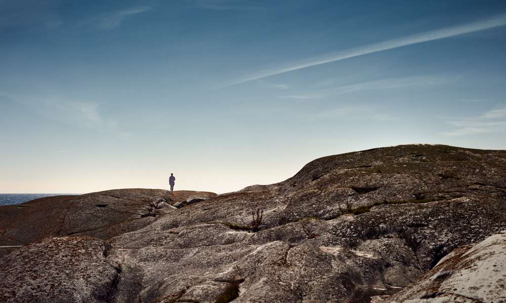 Miljöbild av person på klippor i havsbandet.