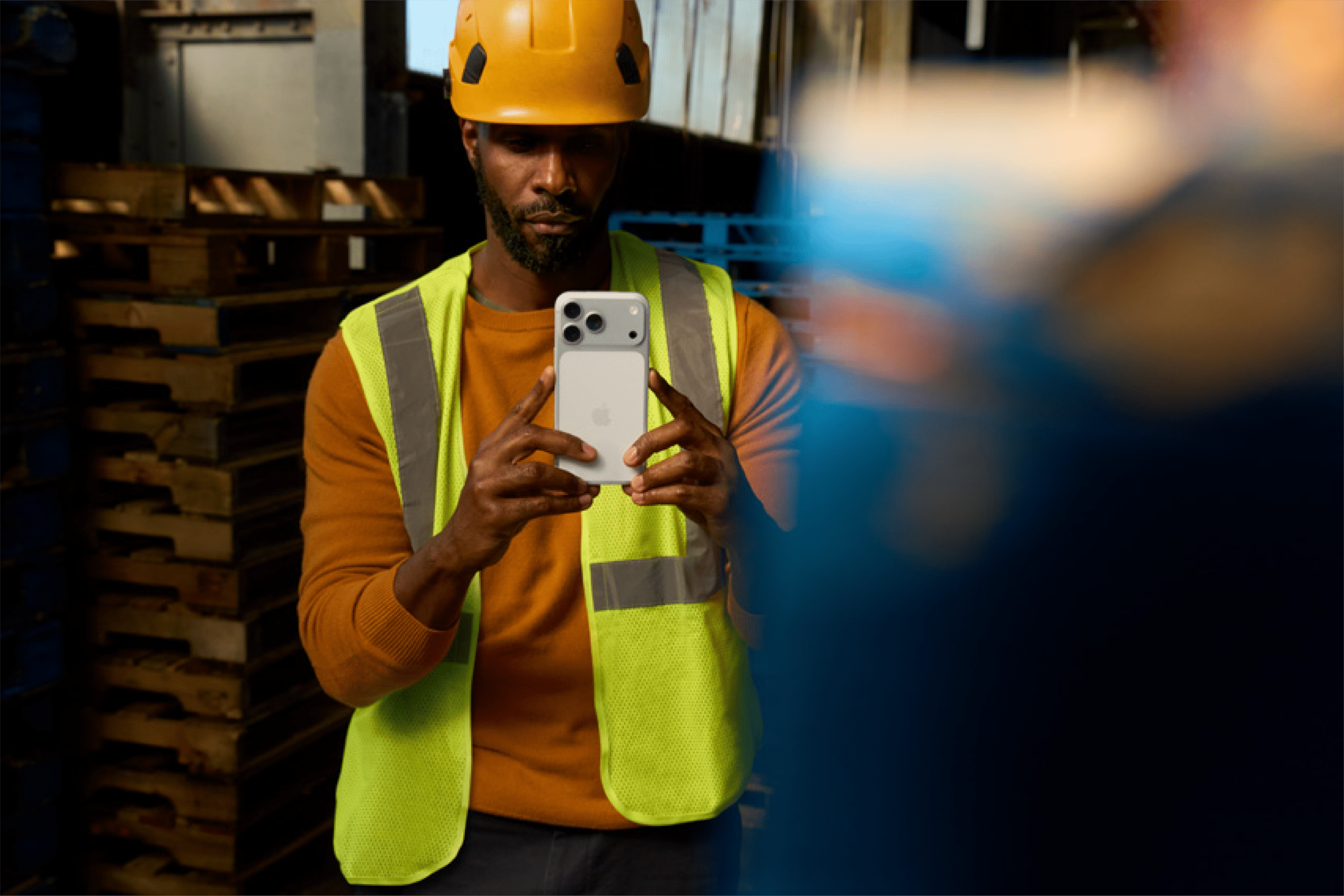 Man med signalväst och skyddshjälm fotar med iPhone 17 Pro