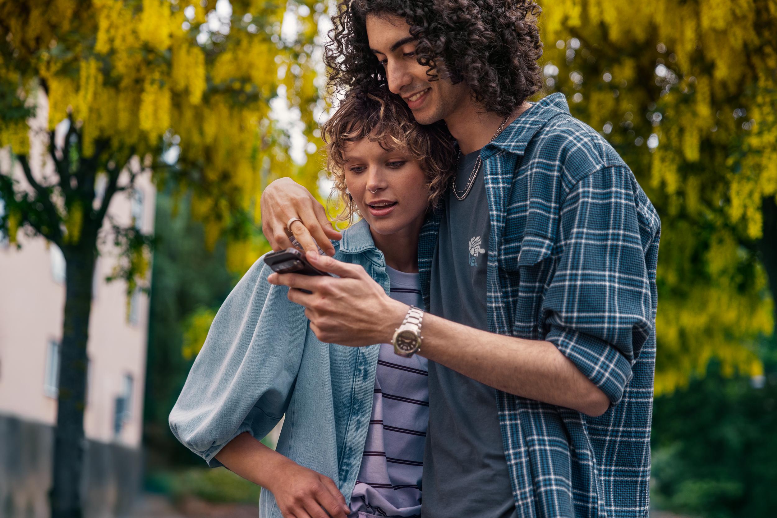 Två personer som kollar i mobil