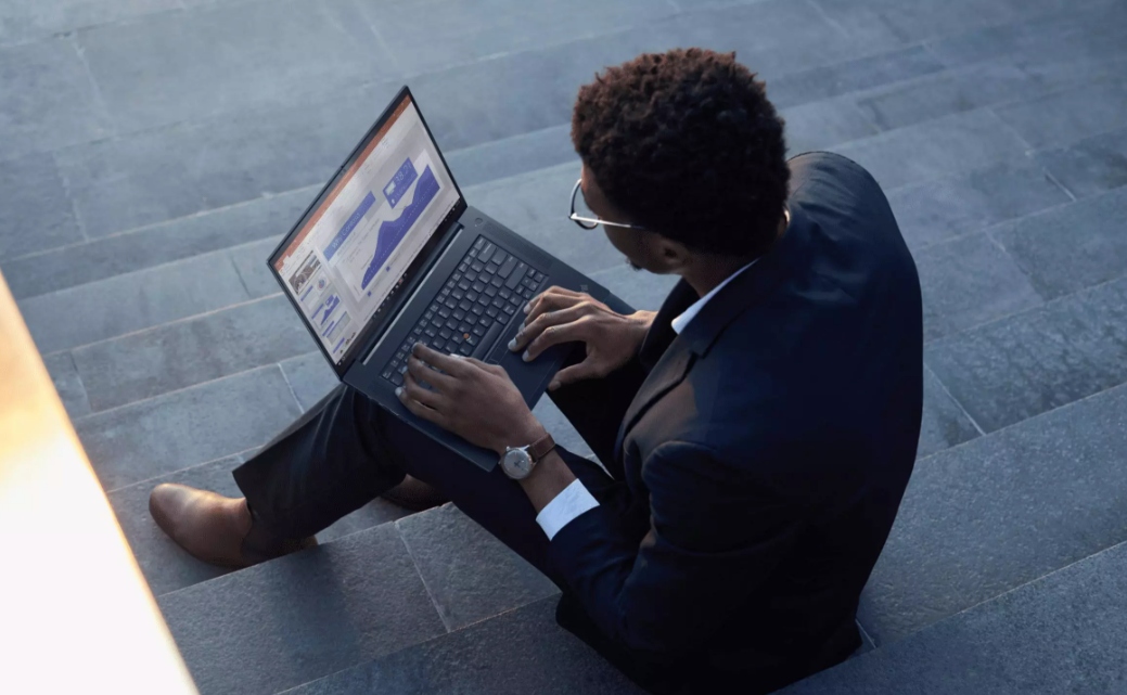 Man med kostym sitter i trappa med Lenovo laptop i knät.