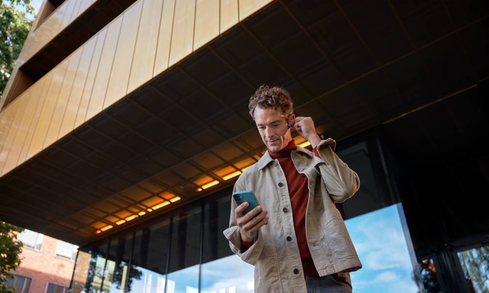 Man utanför byggnad med mobil i handen